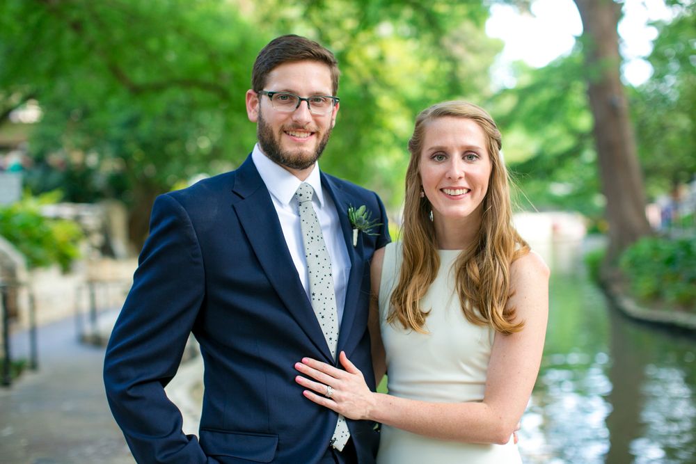 Bride and groom posing together outdoors by water