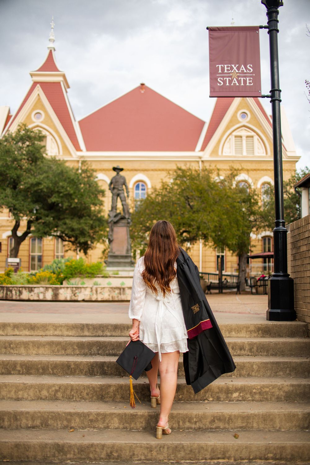 Stone steps leading up to a pink historic university building with gothic architecture.