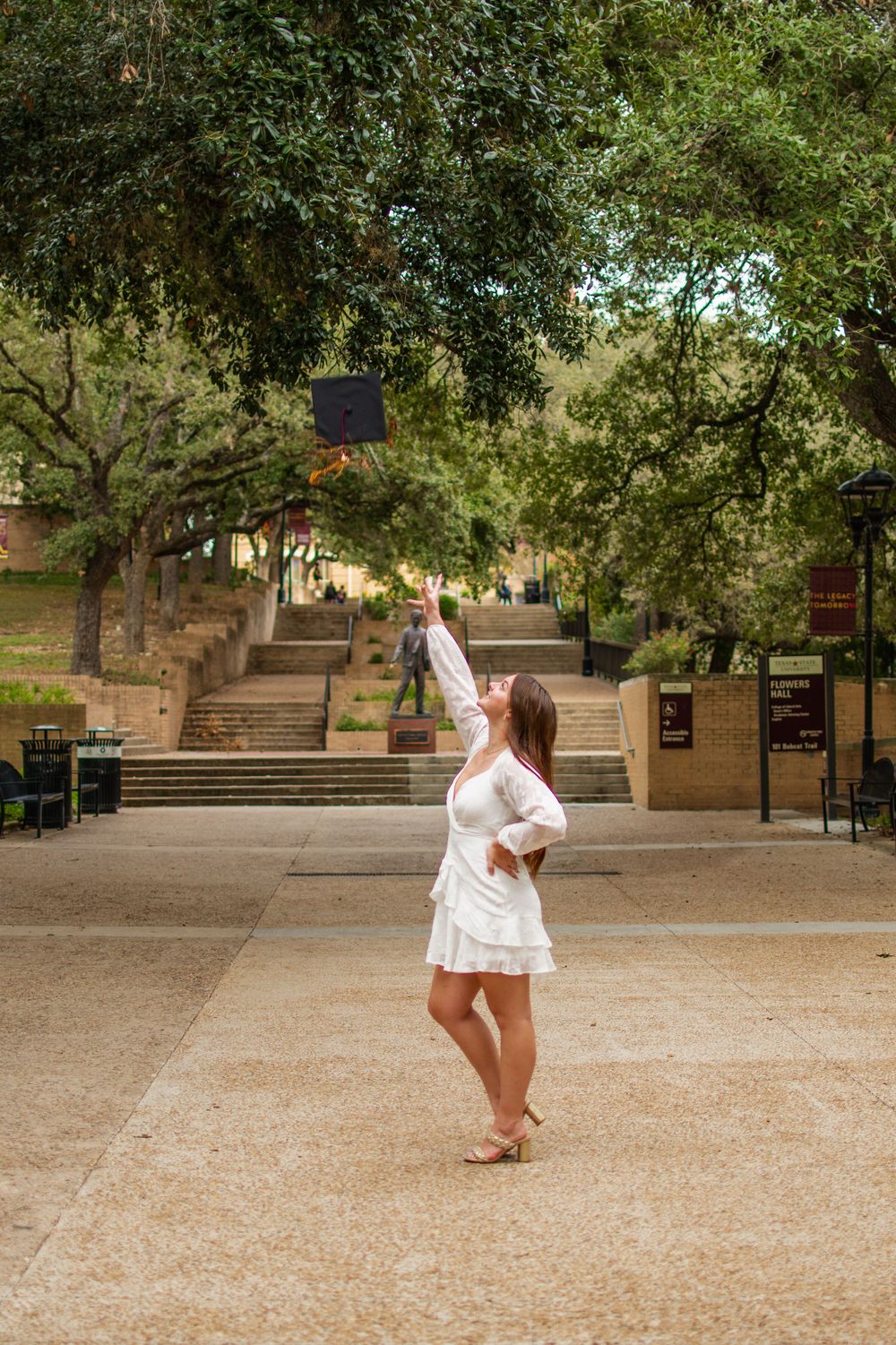 White dress photographed in motion against campus grounds and stone architecture.