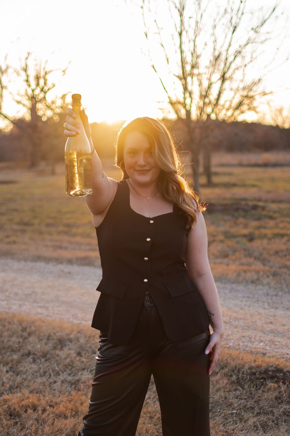 Candid outdoor portrait session during golden hour in rustic field setting.