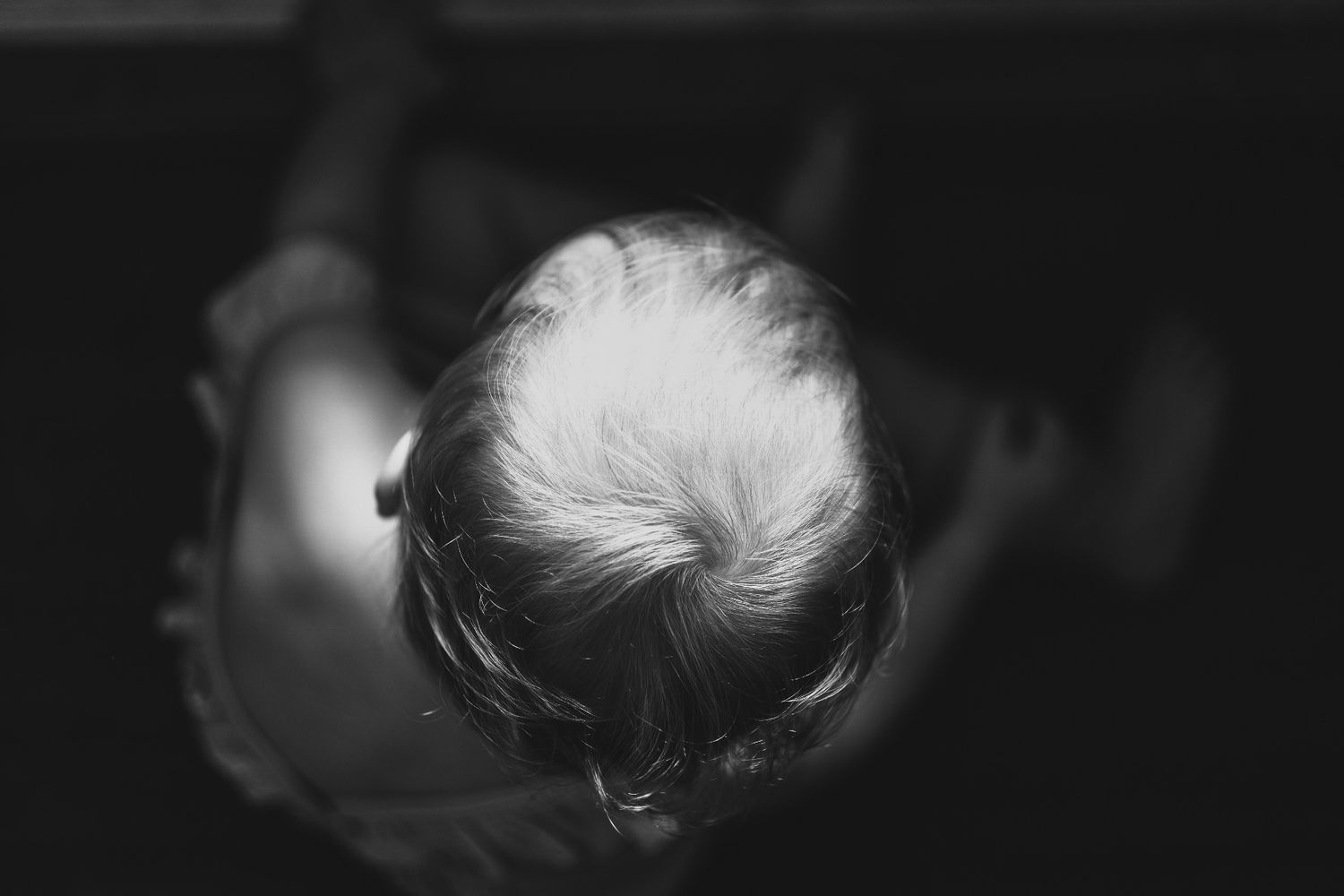 Black and white image of the top of a toddlers head from above
