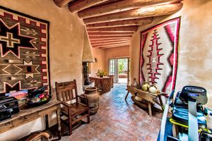 Rustic interior space with exposed wooden beams and terracotta flooring in warm earth tones.
