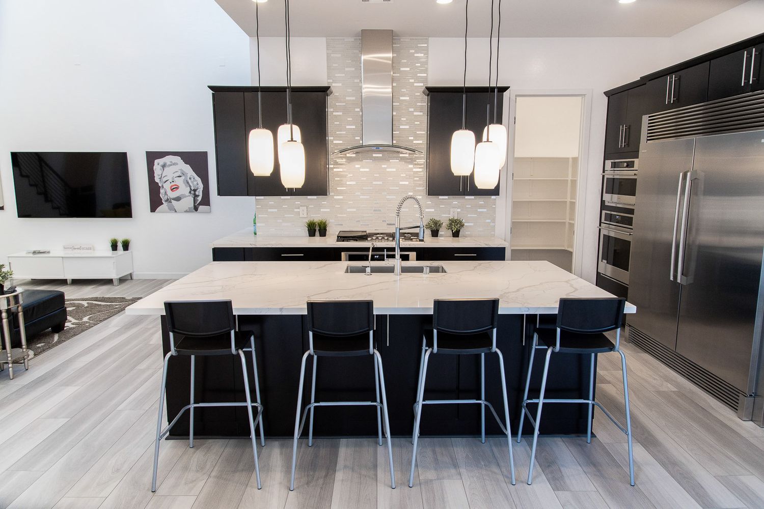 Modern white kitchen with black cabinets and blue bar stools showcasing a sleek contemporary design.
