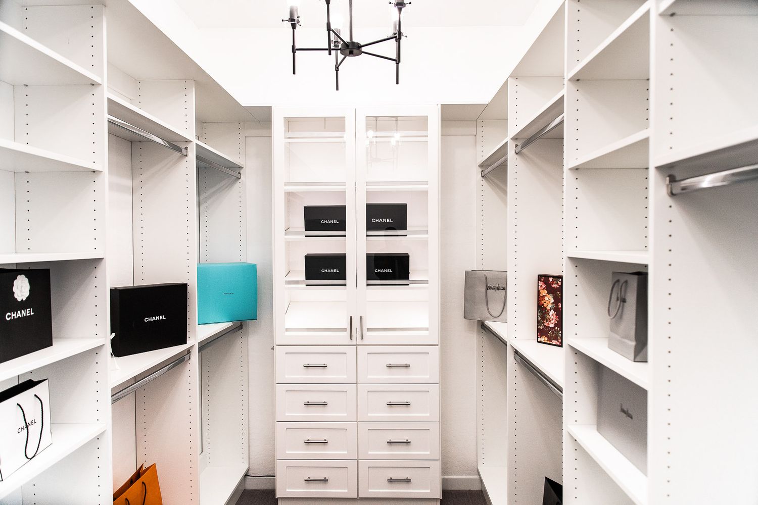 Custom white walk-in closet with built-in shelving, drawers, and organized storage compartments.