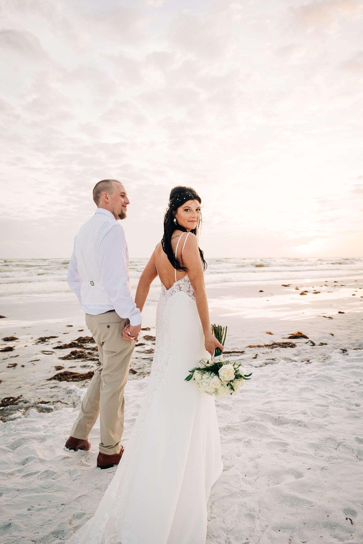 Bride and Groom walking  Siesta Key beach sunset photographed by Sarasota wedding photographer Samantha Brown Artistry.