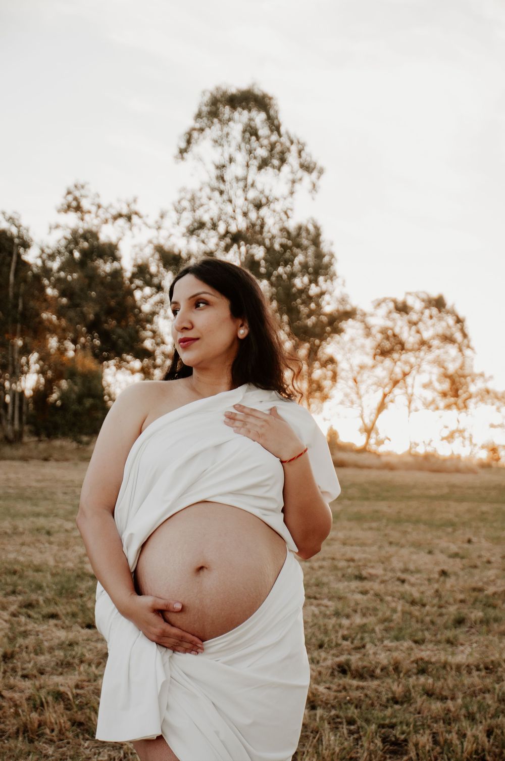 maternity session in a grassy field at sunset