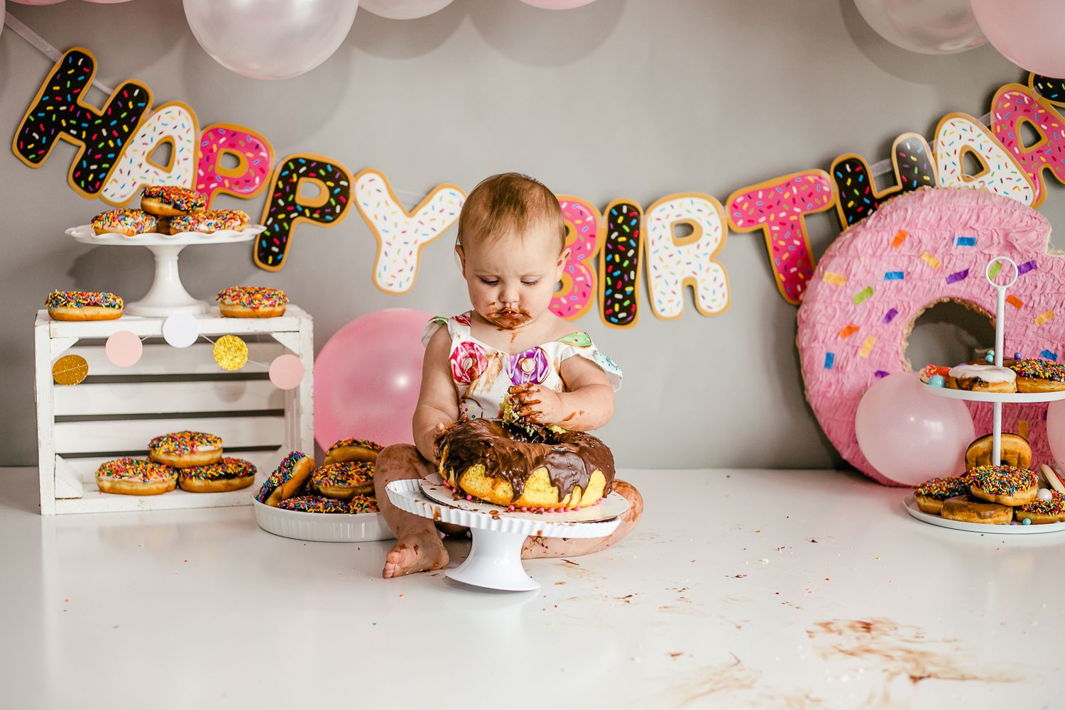 Pink and gold birthday party setup with balloons and dessert table decorations.