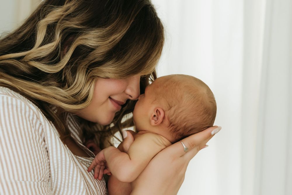 Tender moment between parent and newborn baby in soft natural window light.