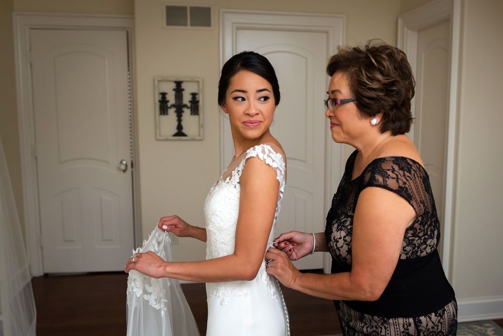 Mother helps bride with dress on wedding day in Akron, Ohio.