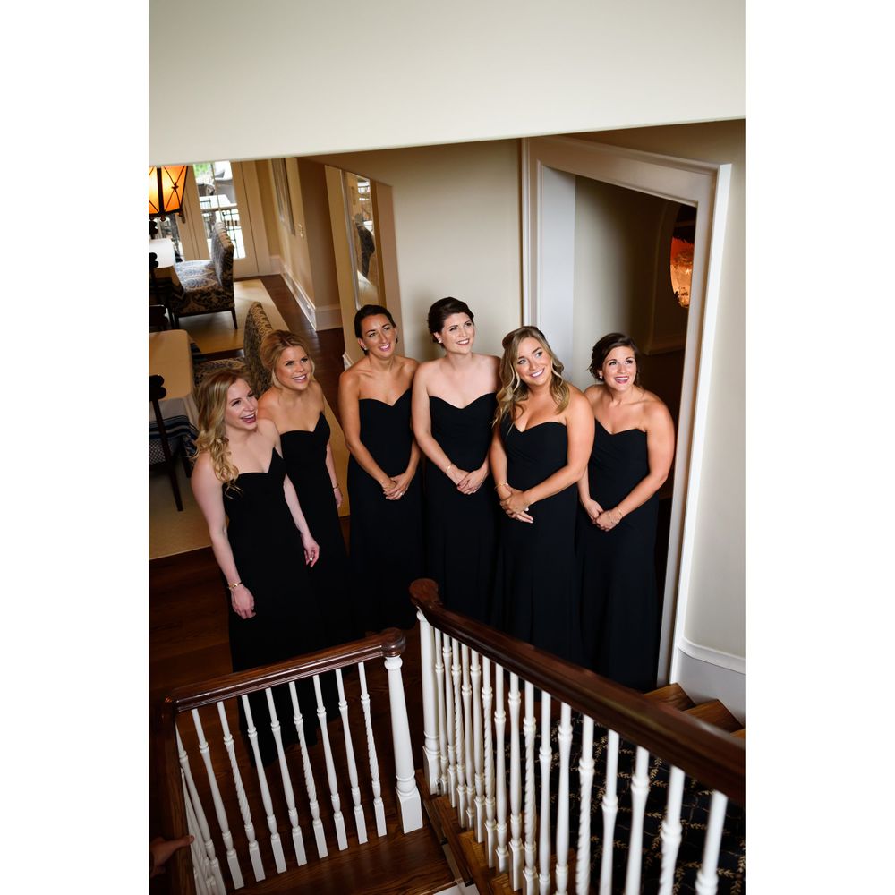 Bridesmaids await bride walking down staircase on wedding day in Akron, Ohio.
