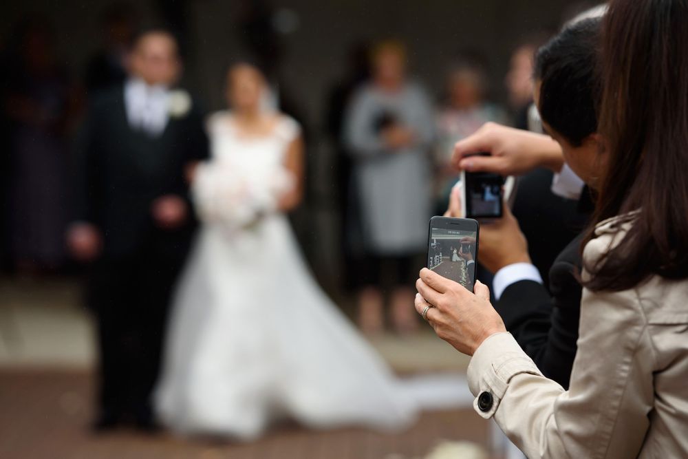 Guests capture pictures of bride walking down aisle on wedding day at Fairlawn Country Club in Akron, Ohio.