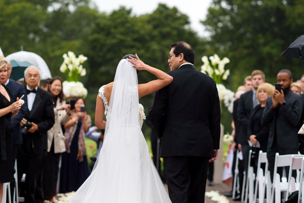 Bride adjusts windblown veil on wedding day at Fairlawn Country Club in Akron, Ohio.