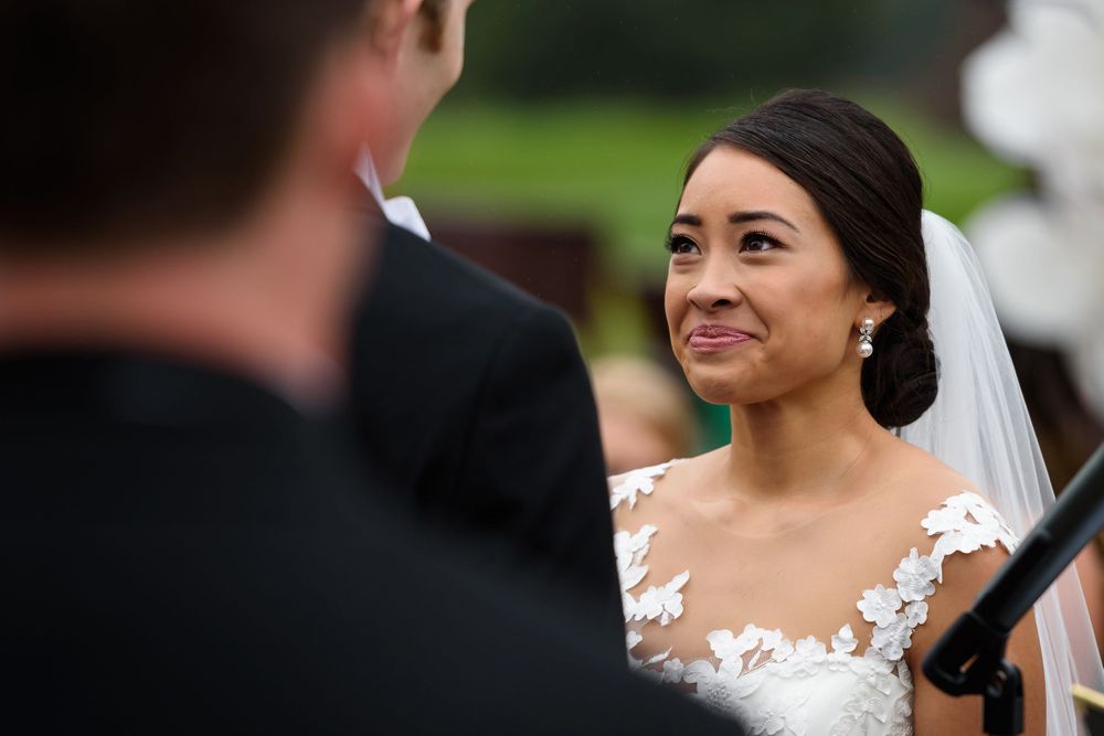 Bride looks into groom's eyes during wedding ceremony at Fairlawn Country Club in Akron, Ohio.