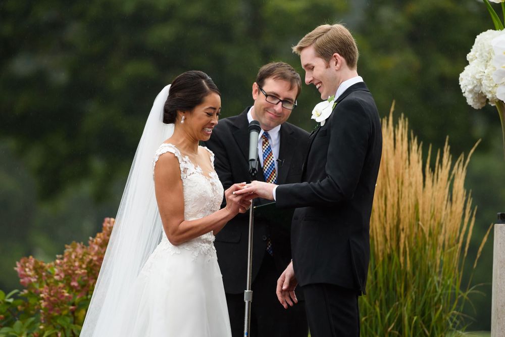 Bride and groom exchange rings during outdoor wedding ceremony at Fairlawn Country Club in Akron, Ohio.