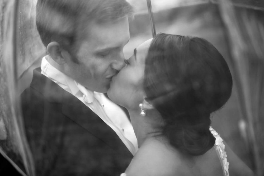Bride and groom snuggle under umbrella during wedding at Fairlawn Country Club in Akron, Ohio.