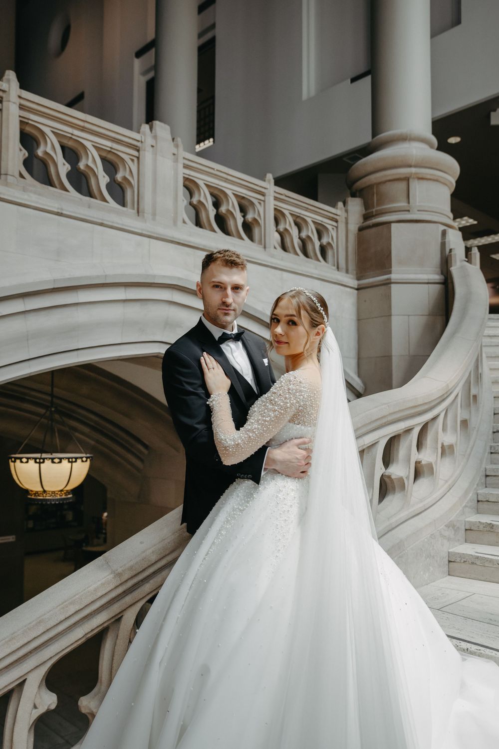 Romantic wedding portrait on a grand marble staircase with architectural details.