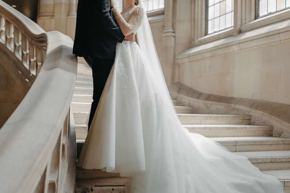 Wedding dress train and couple on classic stone staircase in natural light.