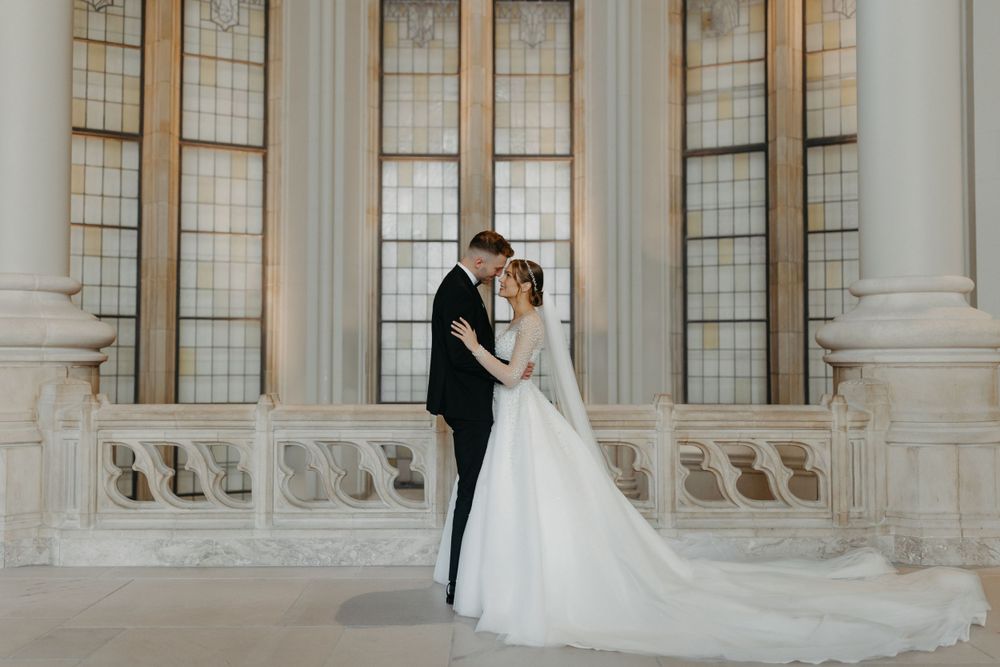 Elegant wedding portrait against classic stone architecture with tall windows.