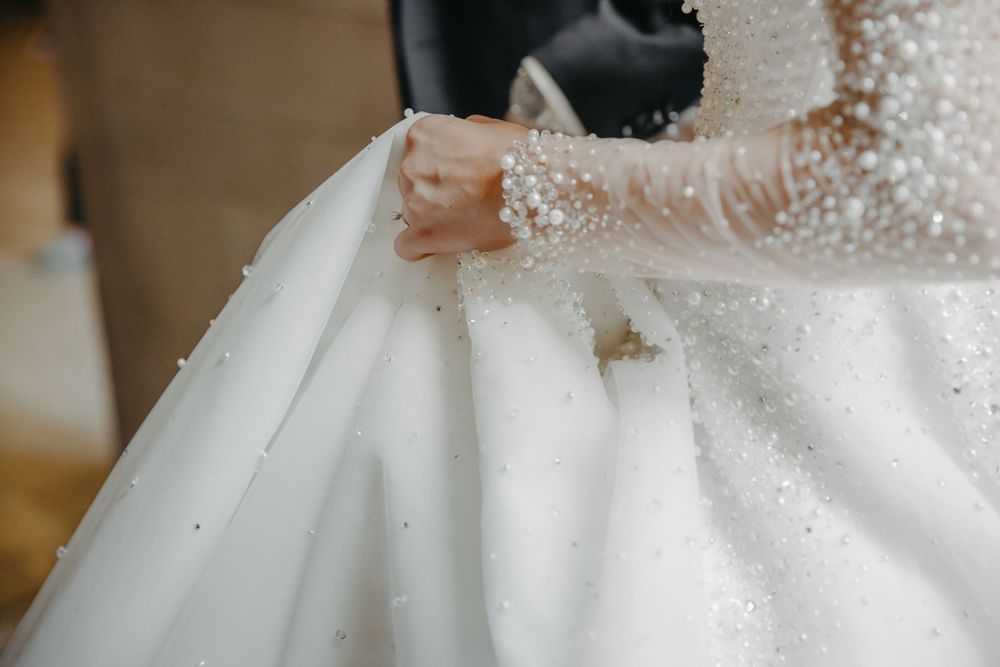 Close-up detail of delicate lace sleeves on a white wedding gown.