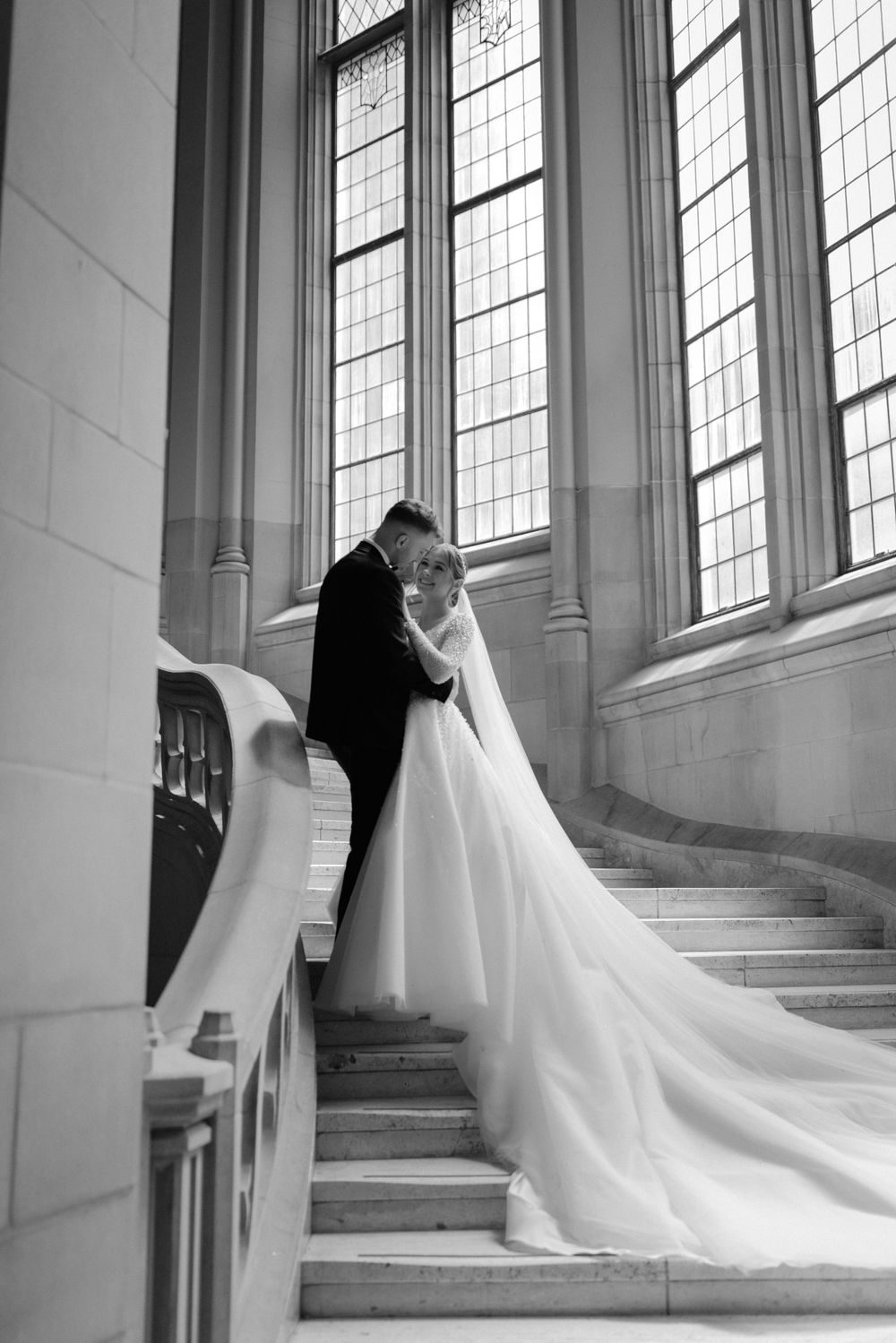 Black and white wedding portrait on grand staircase with dramatic train.