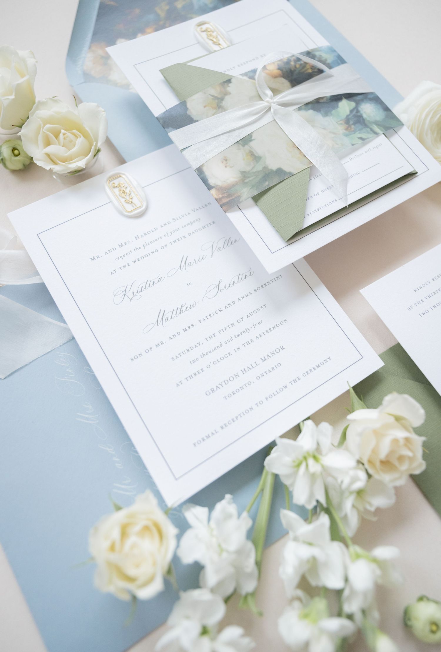 Light blue wedding invitations with white flowers and delicate ribbon details.