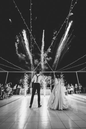 Black and white photo of dancers watching fireworks during their outdoor reception.
