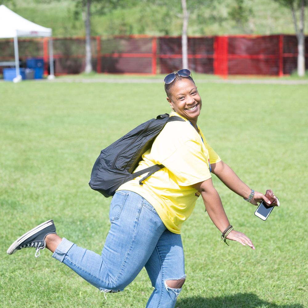 Person in yellow shirt and jeans demonstrates athletic movement sequence on grassy field in bright daylight.