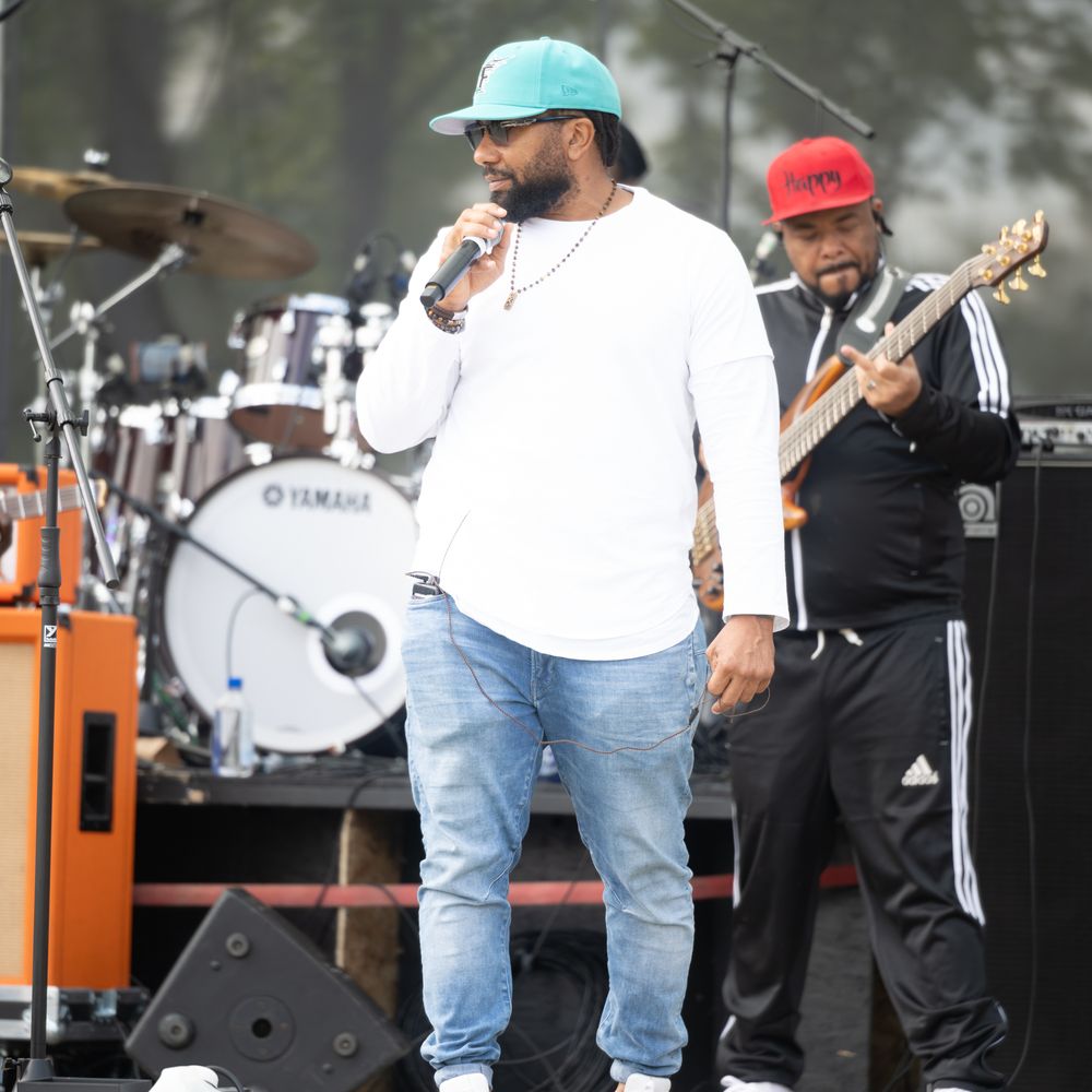 Musicians performing on stage at an outdoor concert with instruments and sound equipment visible.