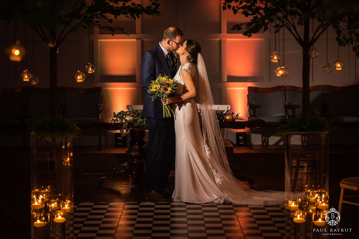 Romantic candlelit wedding ceremony setup with trees and warm lighting.