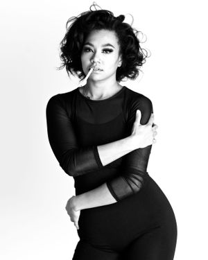 Black and white fashion portrait of a woman in mesh long sleeve bodysuit with dramatic styling.