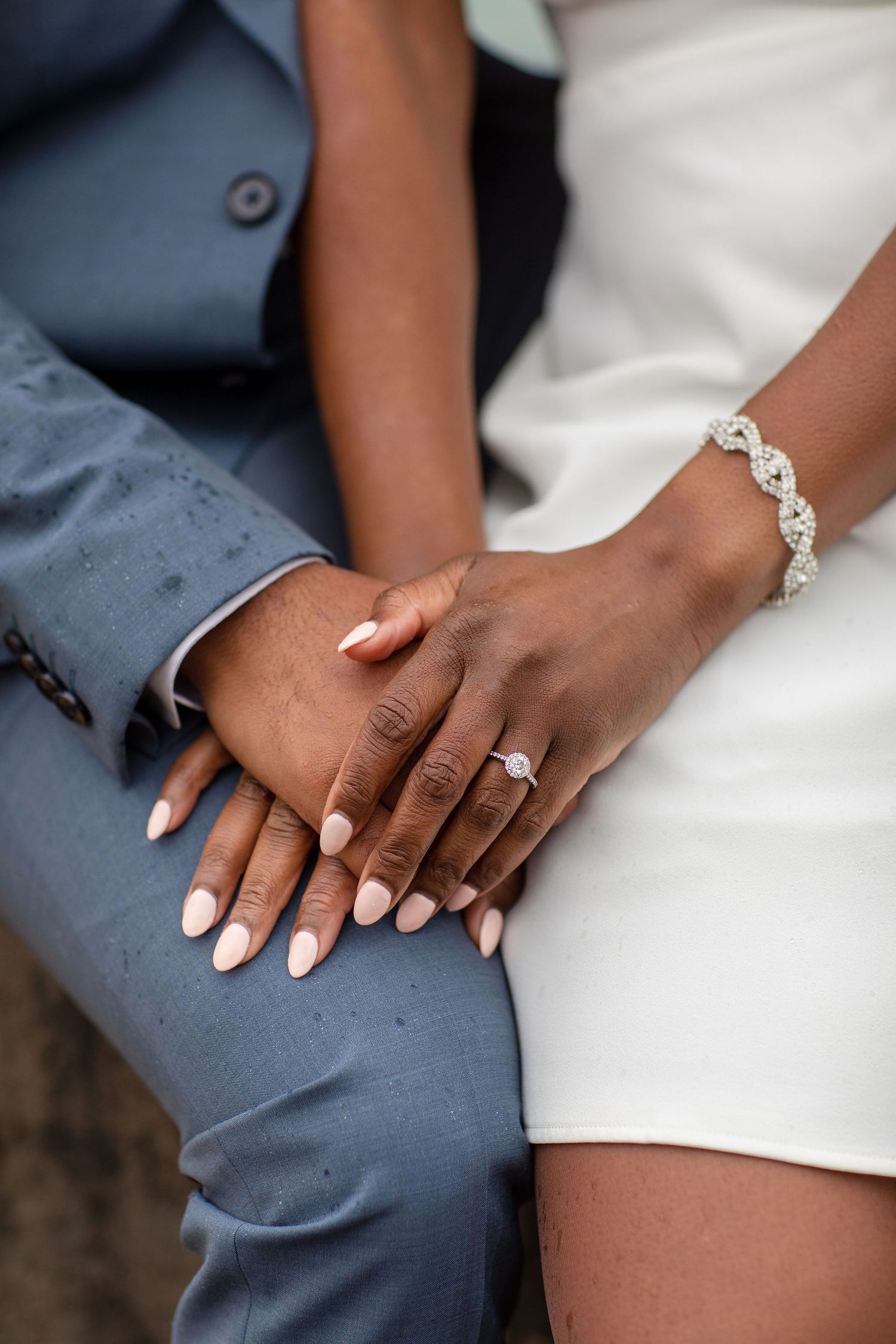 A detailed shot shows clasped hands with an engagement ring and crystal bracelet.