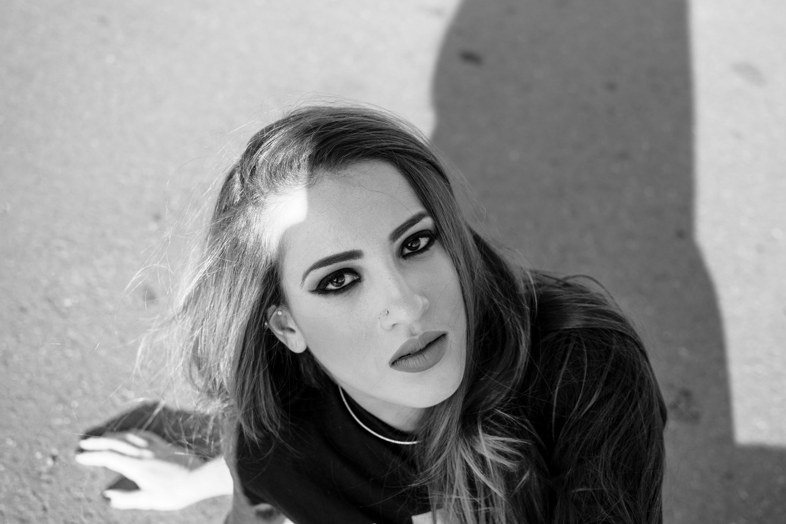 Dramatic black and white portrait against wall with strong shadows.