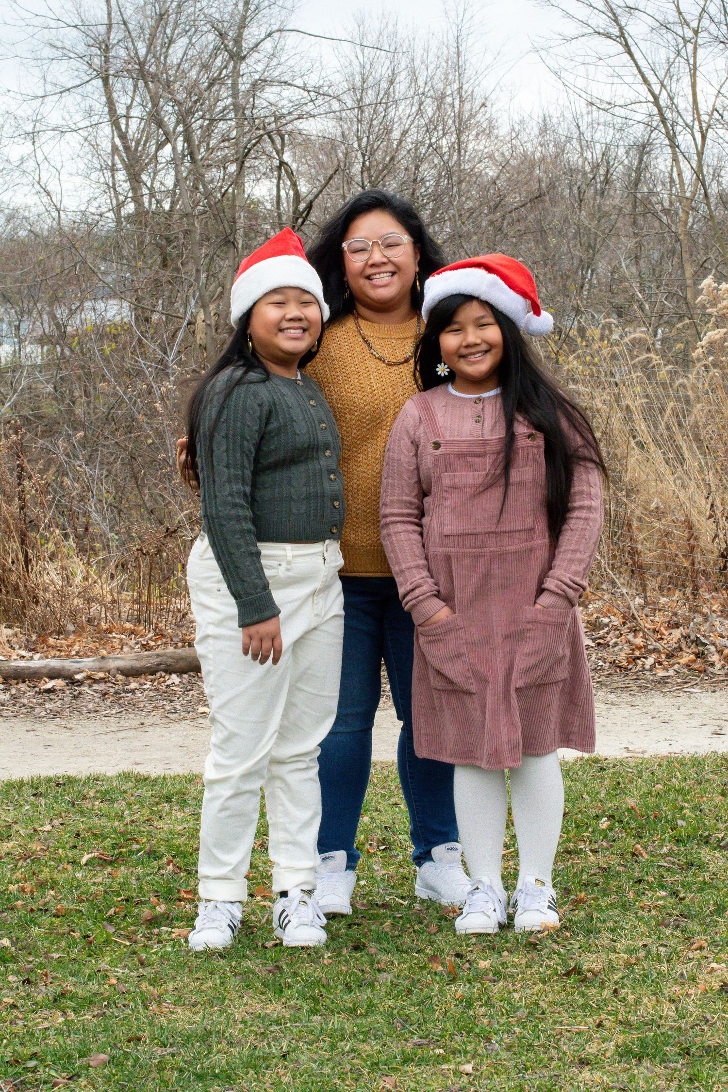 Holiday family photo with group wearing coordinated winter outfits and Santa hats.