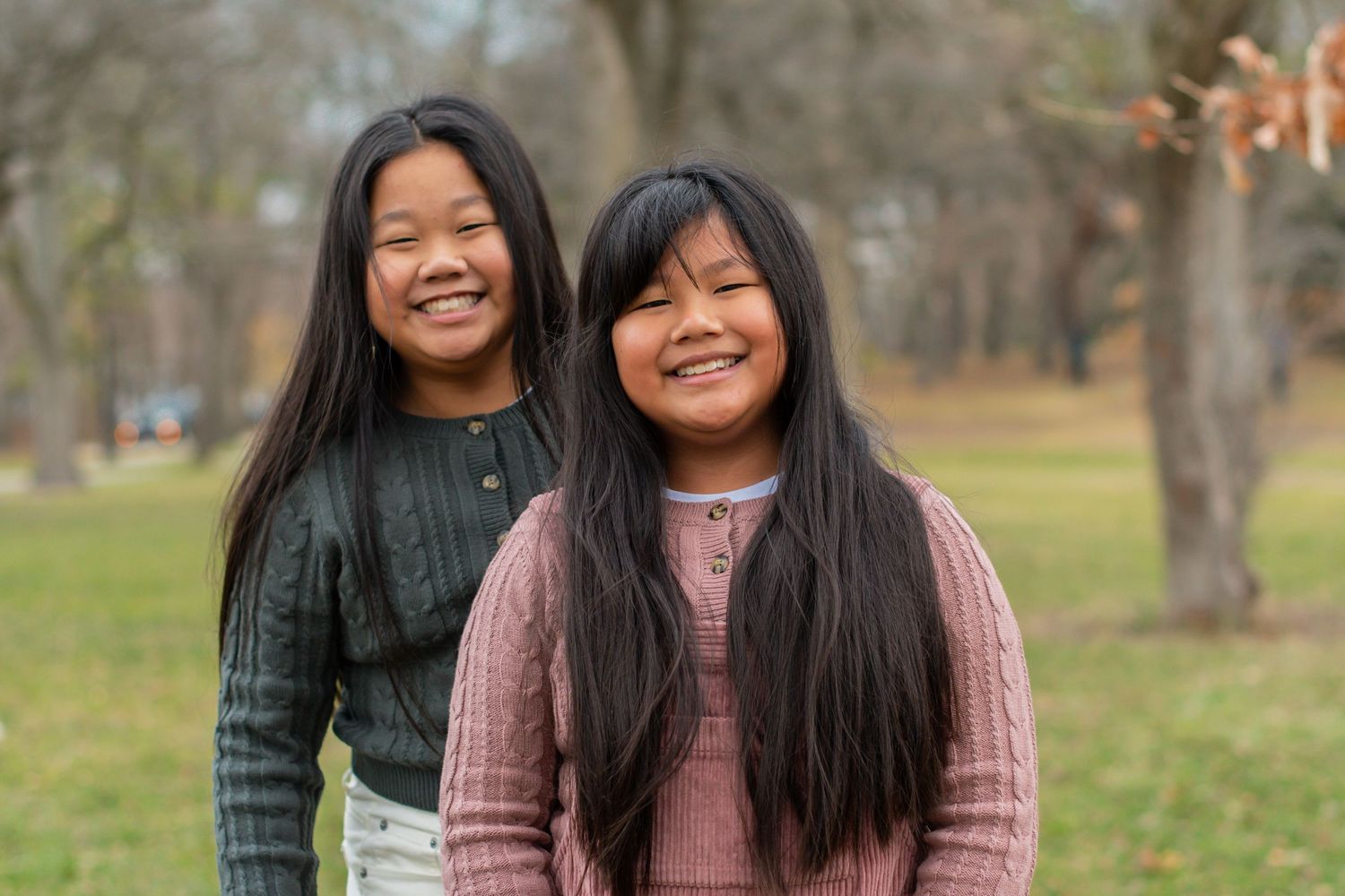 Two friends enjoying autumn weather in cozy sweaters at the park.