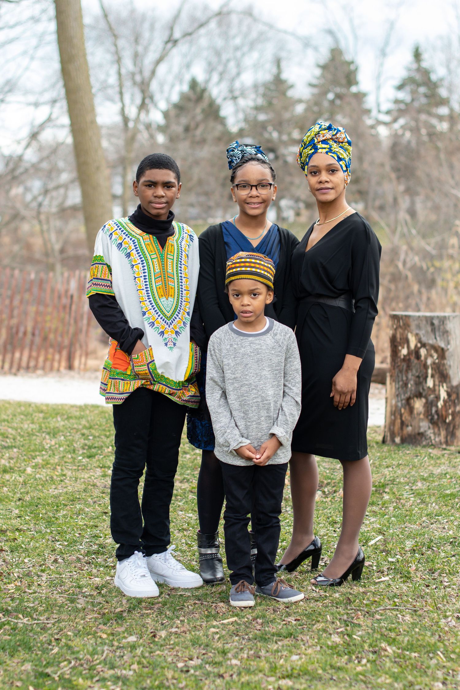 Family group poses outdoors wearing traditional African dashiki prints and casual attire.