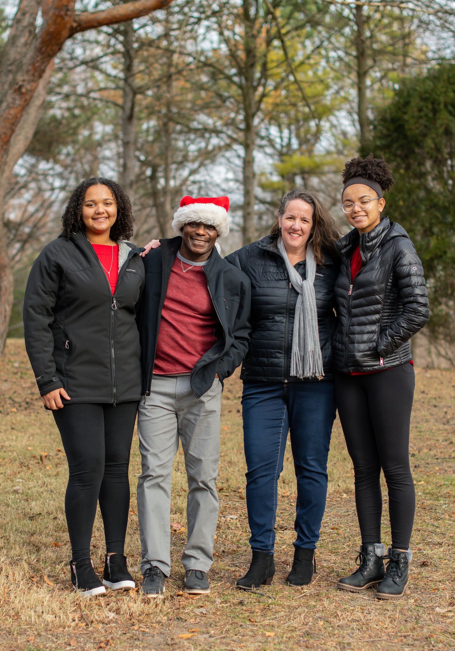 Family members in winter coats pose together for outdoor portrait in autumn setting.