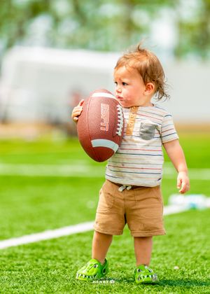 Large group gathers on football field during sports training event.