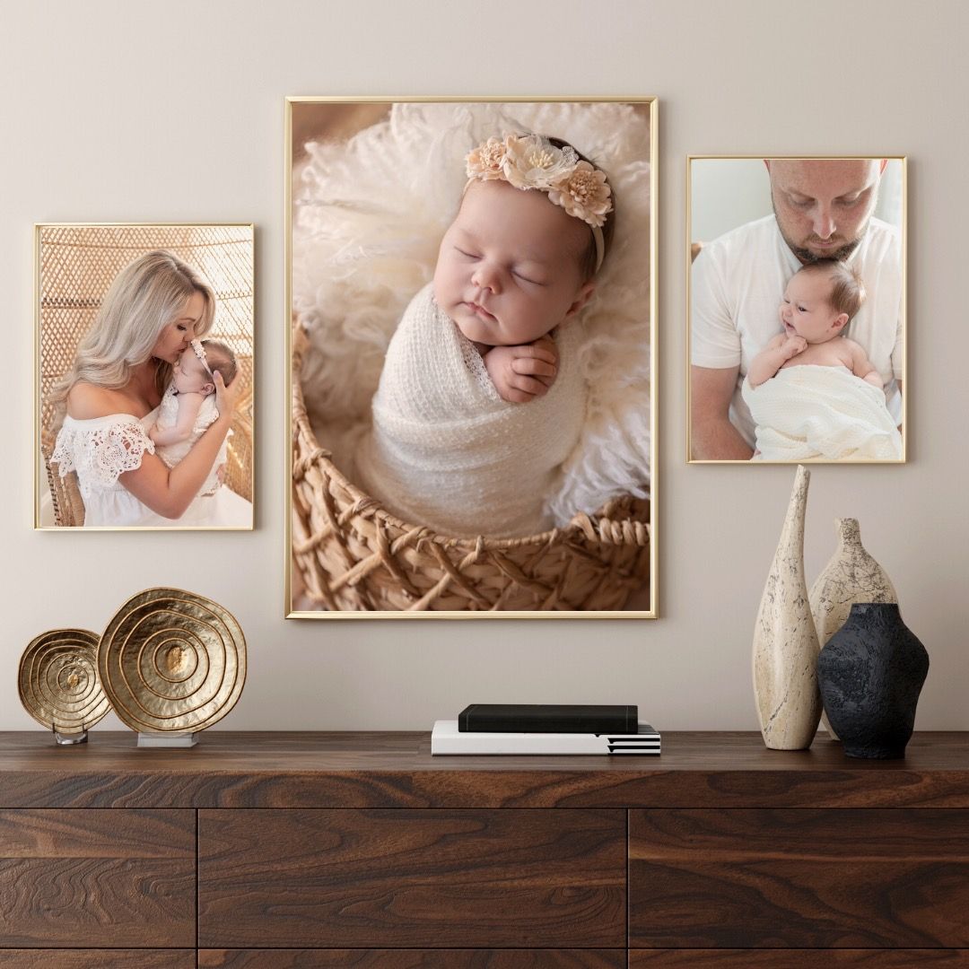 A modern gallery wall display featuring portrait photographs in neutral tones on a wooden console with decorative vases.