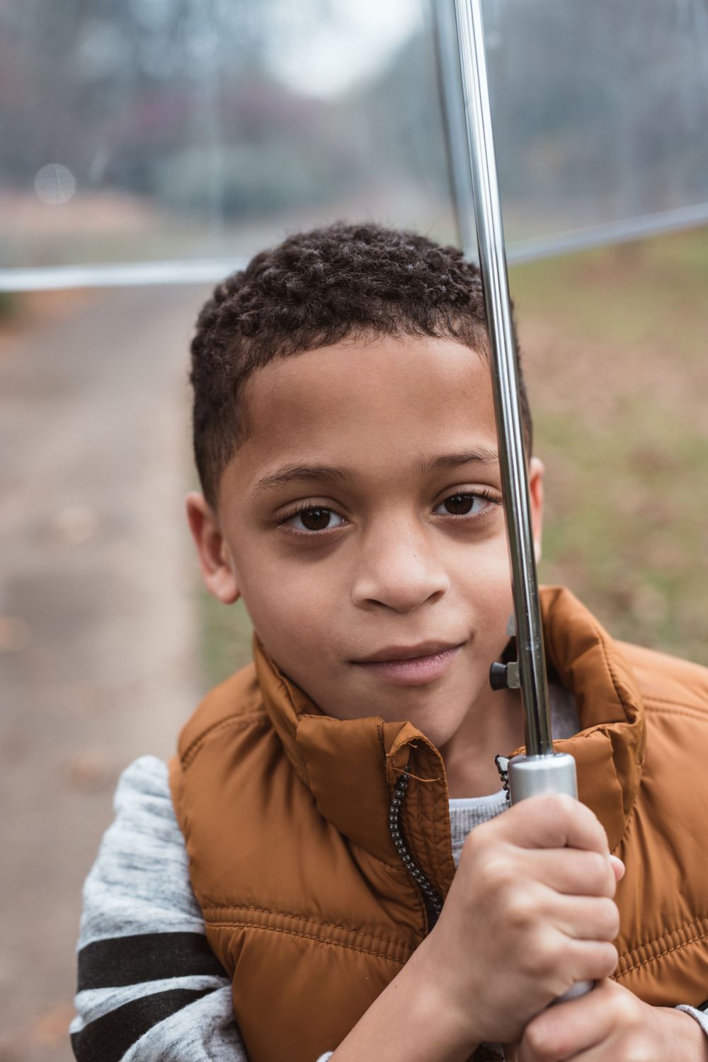 black child holding umbrella while walking down sidewalk