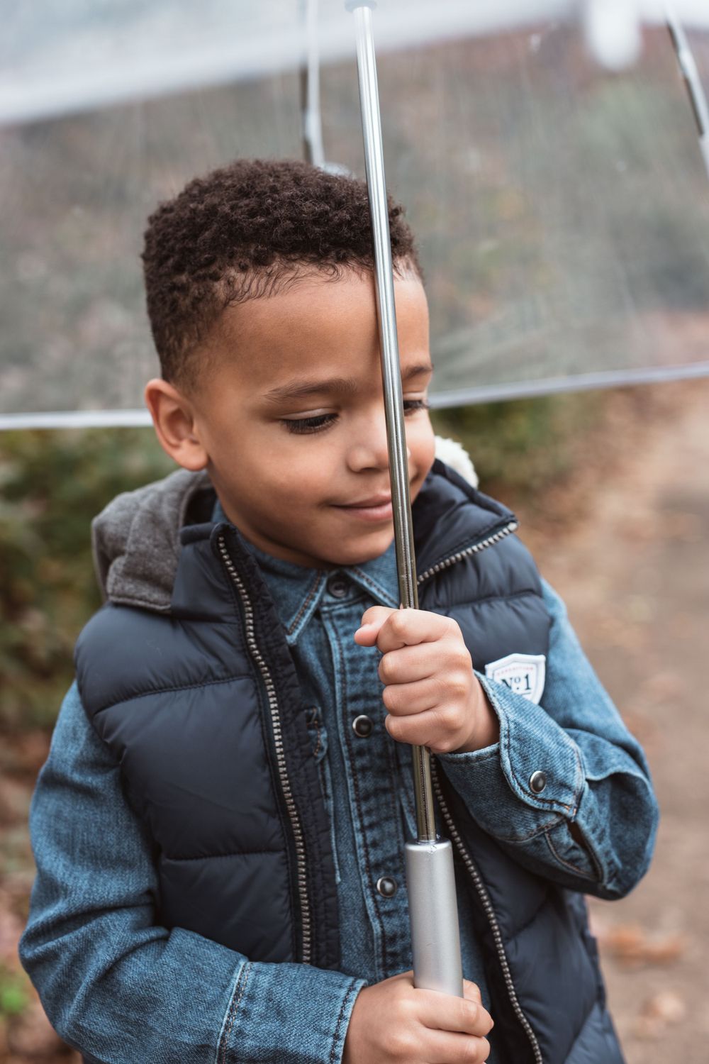 black boy holding umbrella and looking down