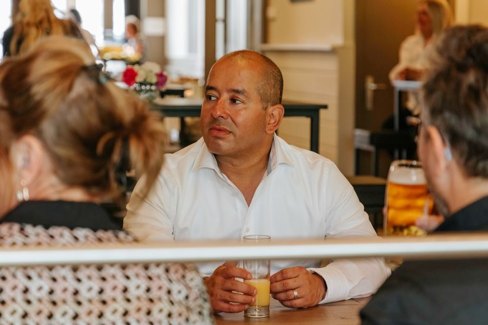 Person sitting at dining table engaged in conversation with others.