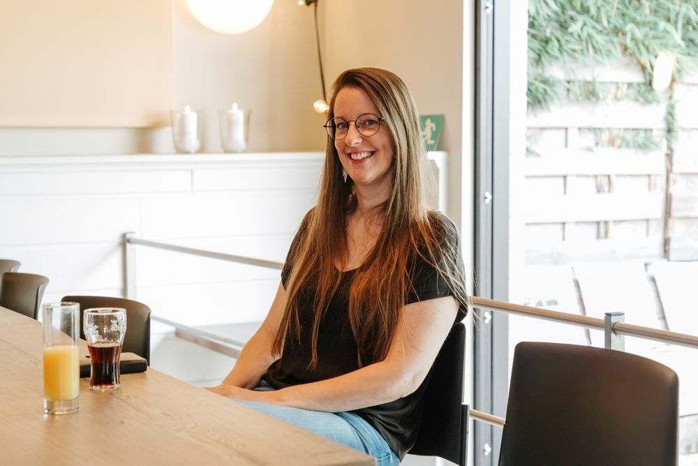 A relaxed casual dining scene with a person smiling at a table near a window.