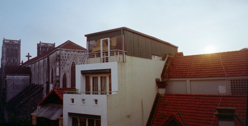 Urban rooftops at sunset with mixed architectural styles and terracotta tiles.
