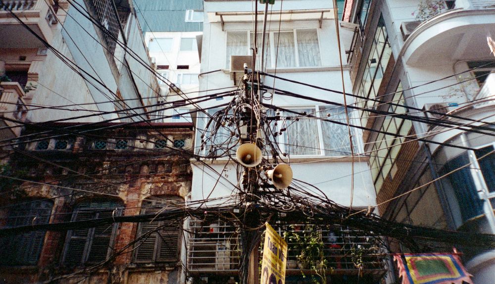 Tangled electrical wires and poles between urban buildings in an Asian city.
