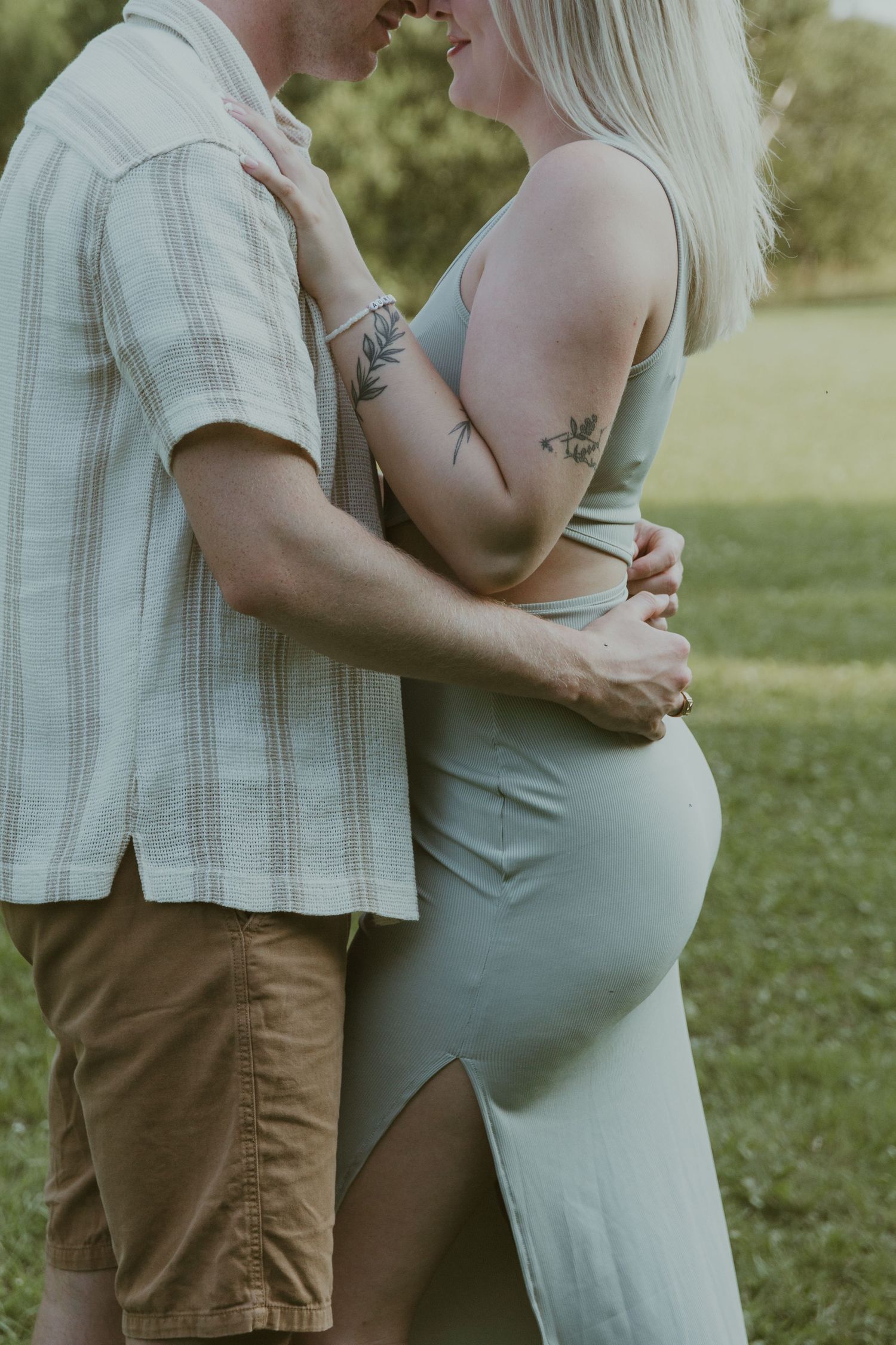 Intimate moment between expecting couple showing baby bump in a green dress.