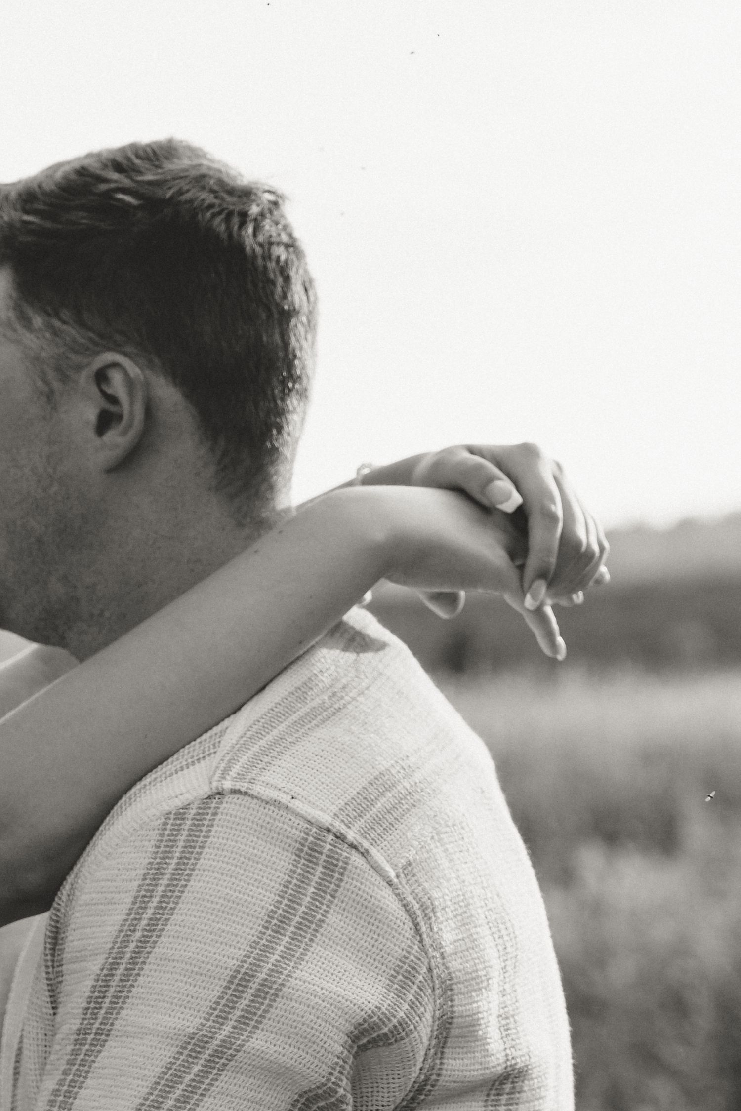 Close-up black and white shot of an intimate embrace outdoors.