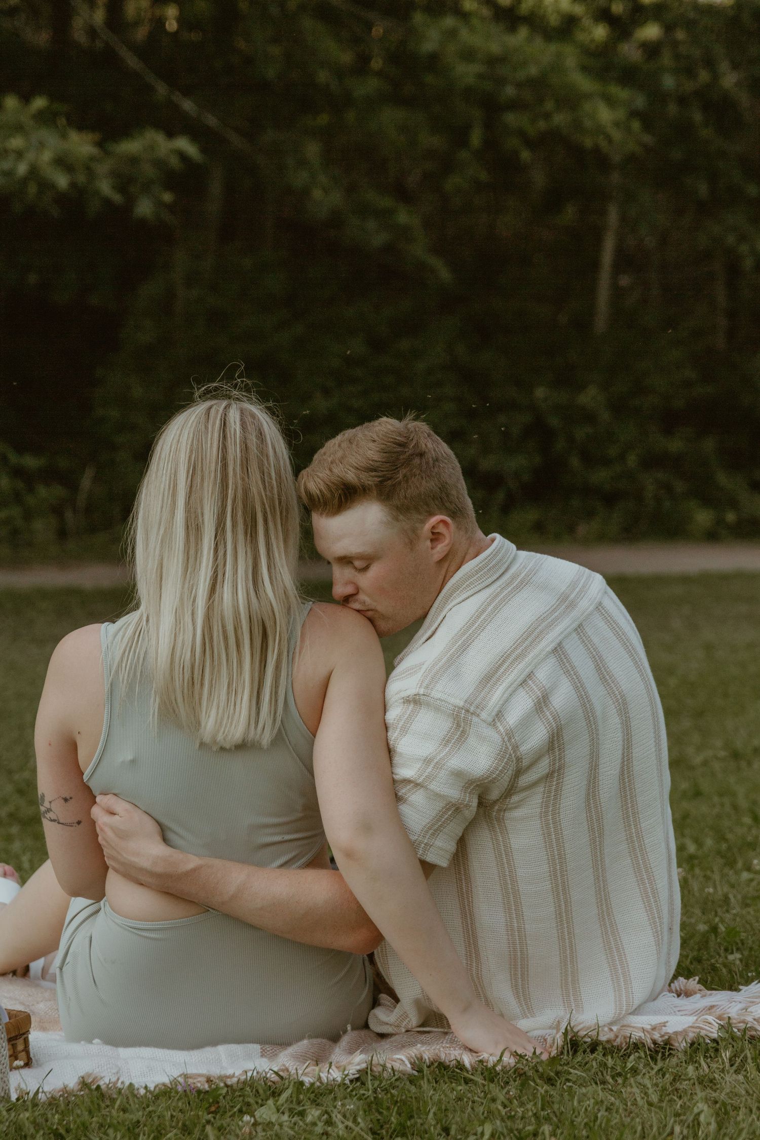 Couple sitting together on picnic blanket in a tranquil garden setting.