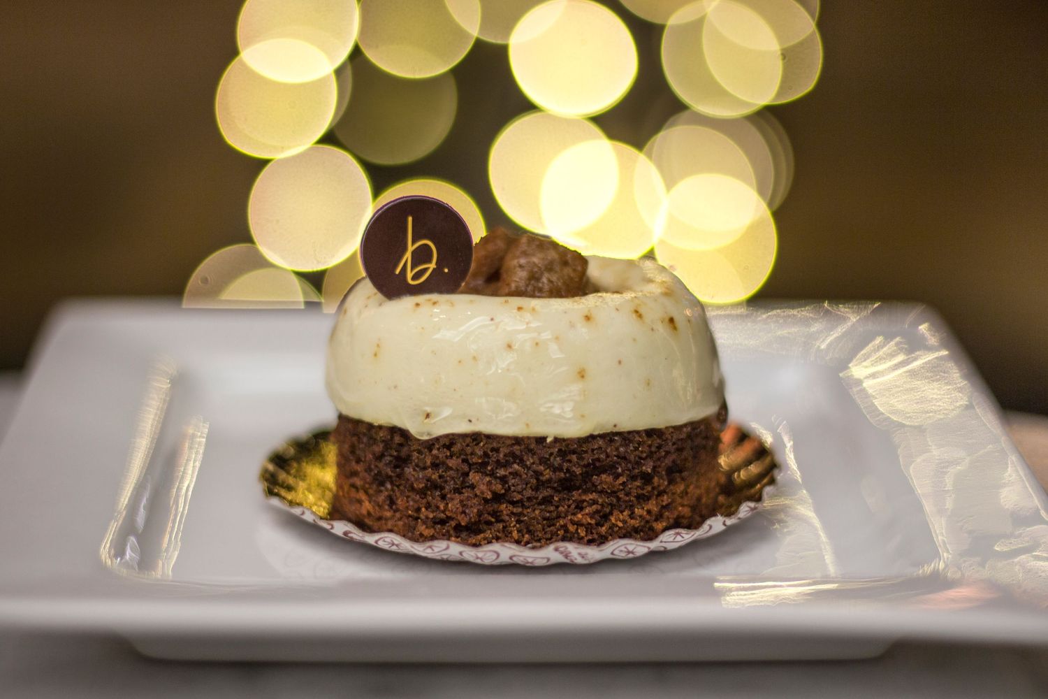 Elegant chocolate dessert with gold decoration photographed against bokeh lights. Product Photography