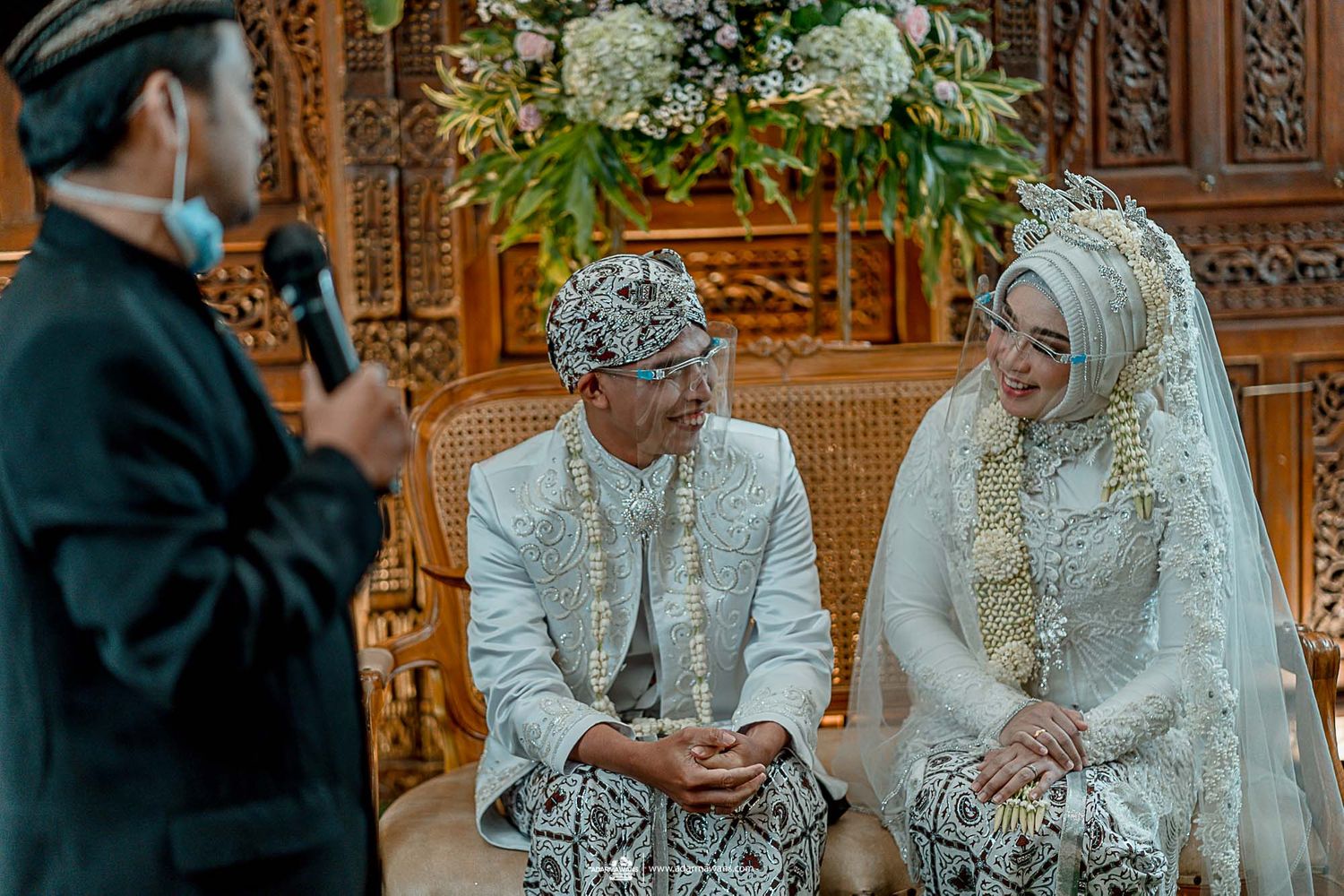 Wedding officiant addresses couple during traditional Indonesian marriage ceremony.