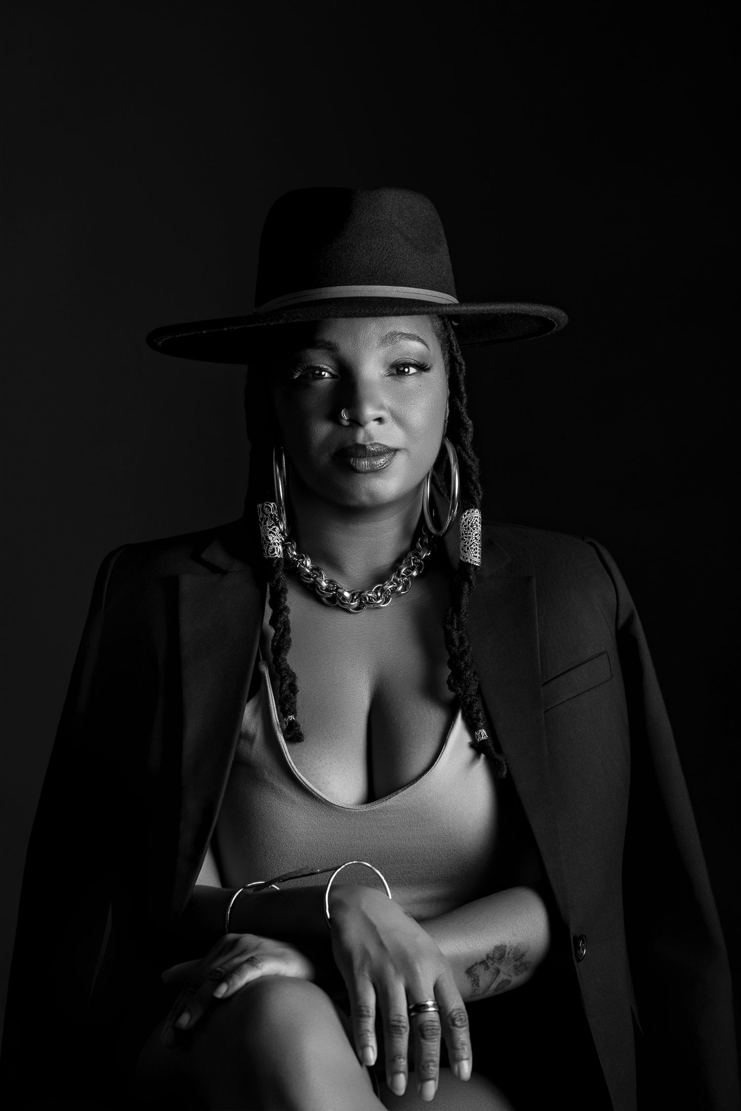 Artistic black and white portrait series featuring dramatic lighting, jewelry, and a fashionable hat in a moody setting.